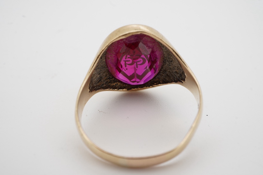 A 9ct and synthetic ruby set signet ring, the stone carved with gilded masonic symbol, size S/T, gross weight 5.8 grams. Condition - fair to good